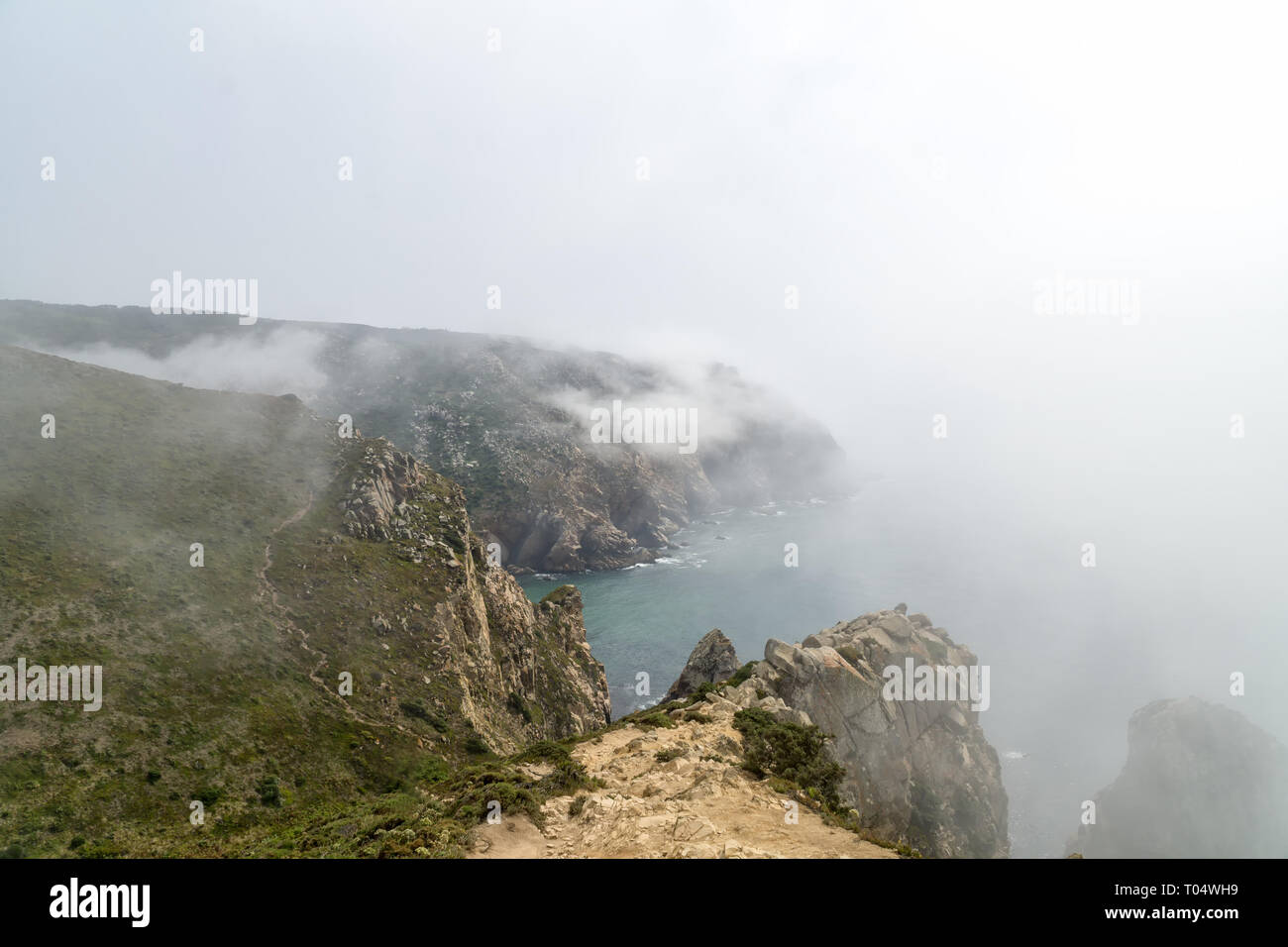 Cabo de Roca (Cabo da Roca) acantilados en la niebla. Las rocas están oscurecidas por las nubes o la niebla. Cabo Roca es parte más occidental de Europa, Portugal. Foto de stock