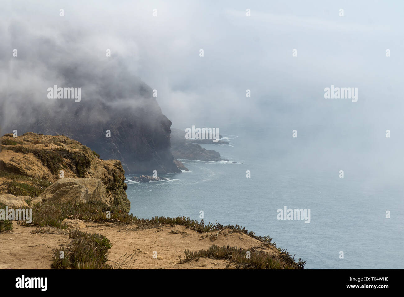 Cabo de Roca (Cabo da Roca) acantilados en la niebla. Las rocas están oscurecidas por las nubes o la niebla. Cabo Roca es parte más occidental de Europa, Portugal. Foto de stock