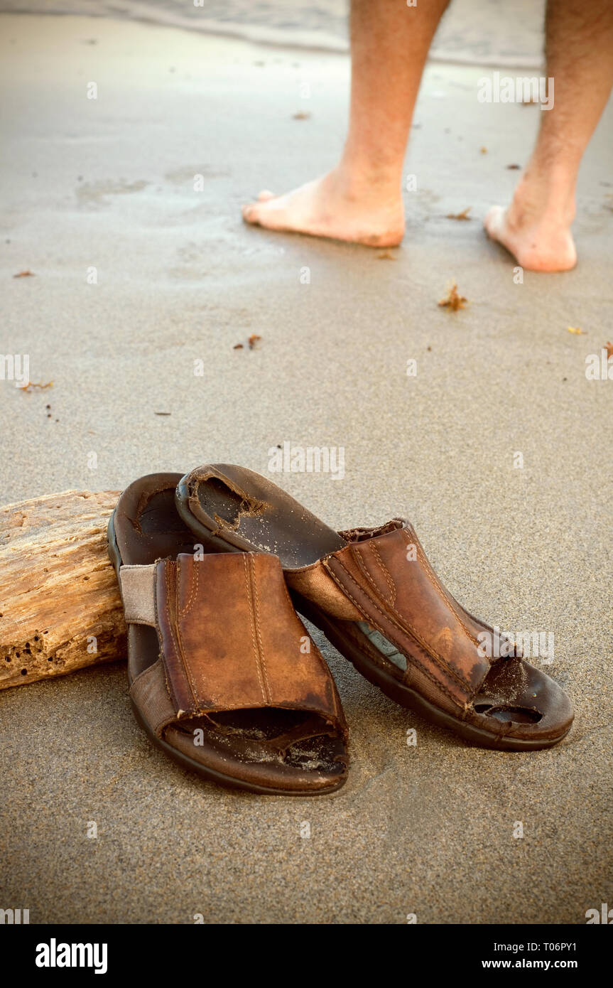 Persona de pie en la playa tropical con viejas sandalias de cuero  desgastada detrás de él Fotografía de stock - Alamy