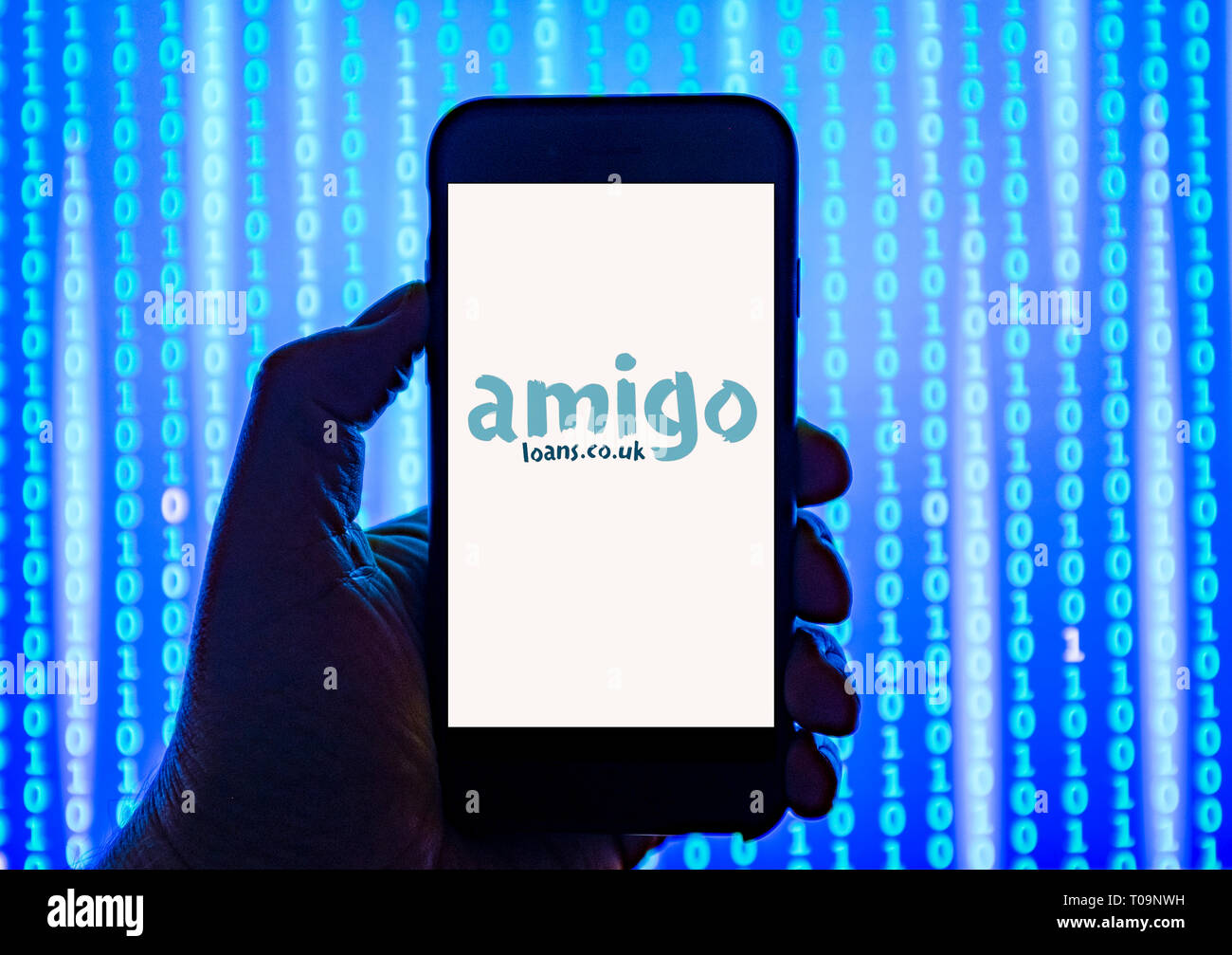 Persona sosteniendo el teléfono inteligente con Amigo.co.uk préstamos el logotipo de la empresa aparece en la pantalla. Foto de stock