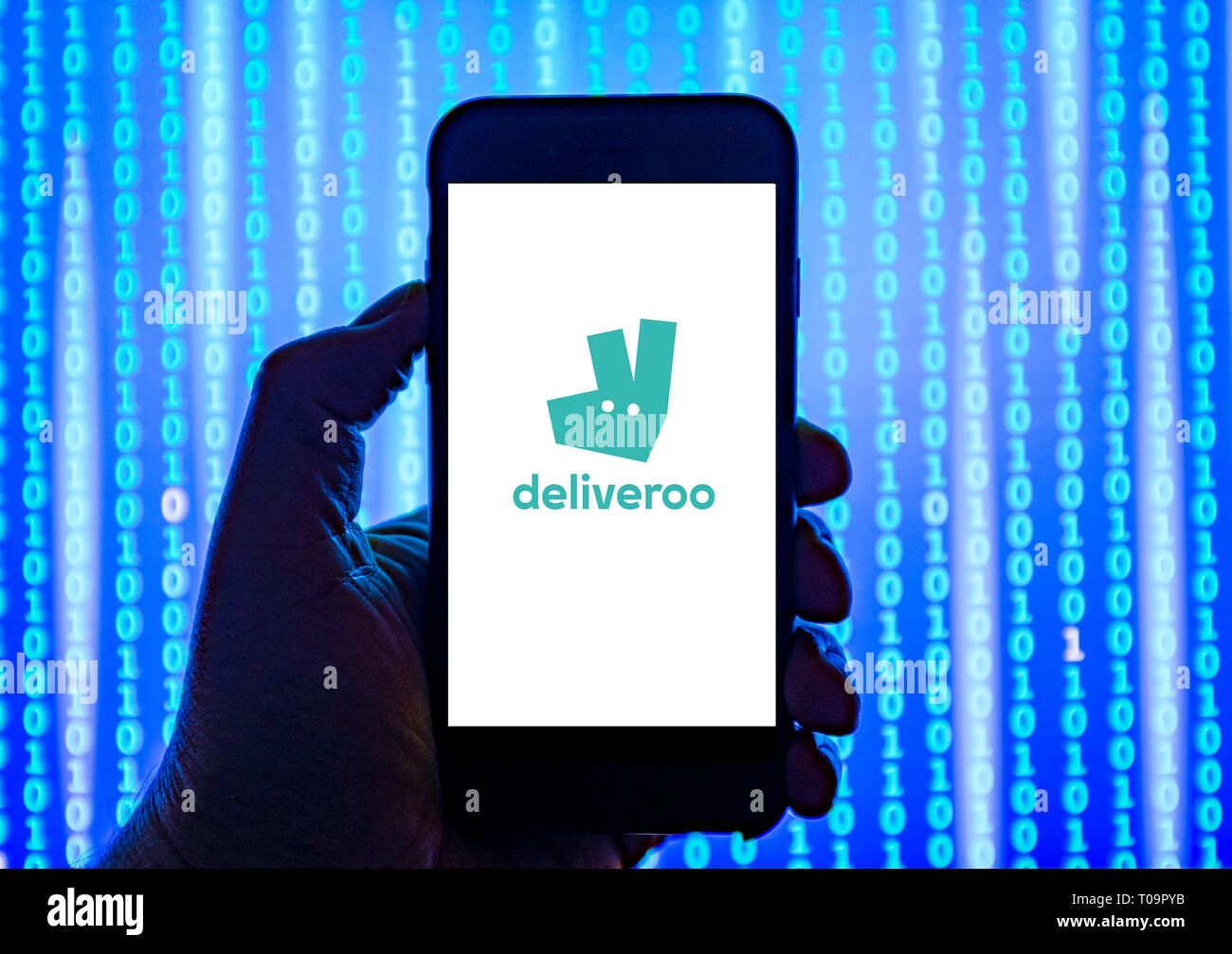 Persona sosteniendo el teléfono inteligente con Deliveroo Logotipo mostrado en la pantalla. Foto de stock