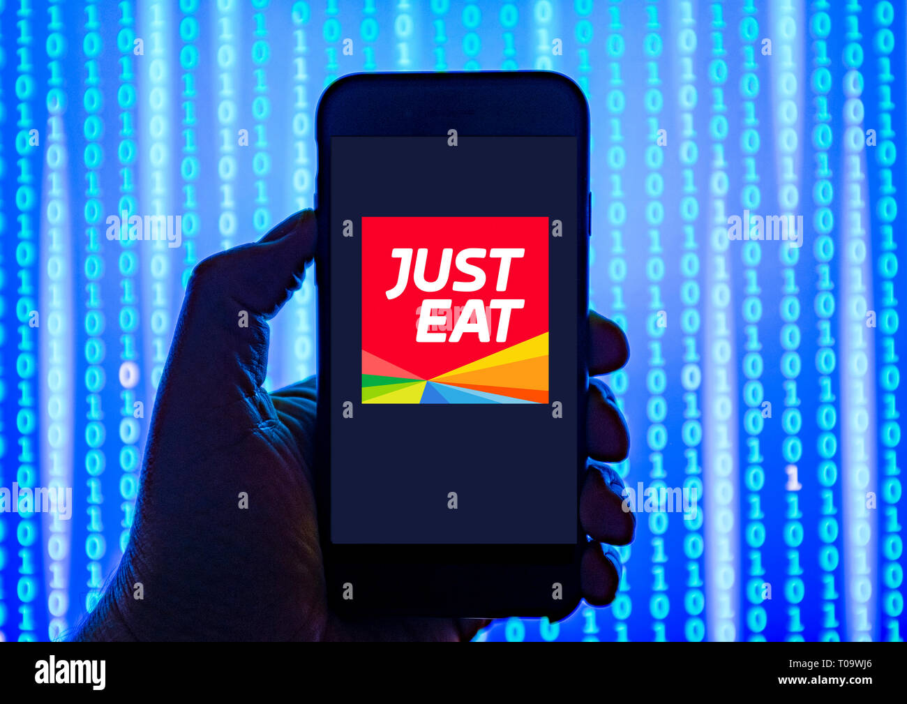 Persona sosteniendo el teléfono inteligente con comer sólo el servicio de entrega de alimentos logotipo mostrado en la pantalla. Foto de stock