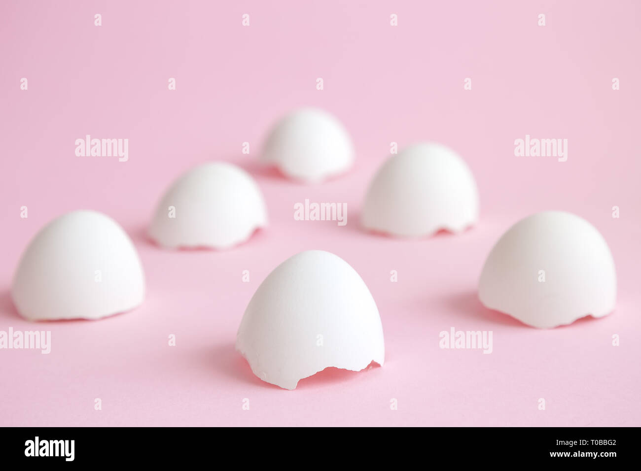 Las cáscaras de huevo blanco contra el fondo de color rosa pastel