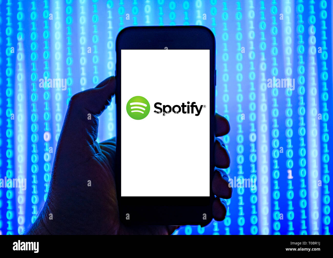 Persona sosteniendo el teléfono inteligente con servicio de streaming de música Spotify Logotipo mostrado en la pantalla. Foto de stock