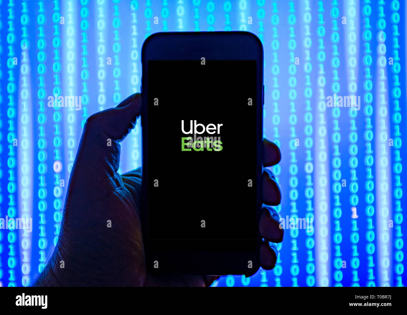 Persona sosteniendo el teléfono inteligente con Uber come alimentos pedidos y entrega servicio logo aparece en la pantalla. Foto de stock