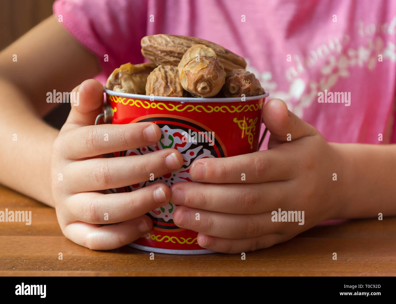 Kid manos sosteniendo un plato de fechas Foto de stock