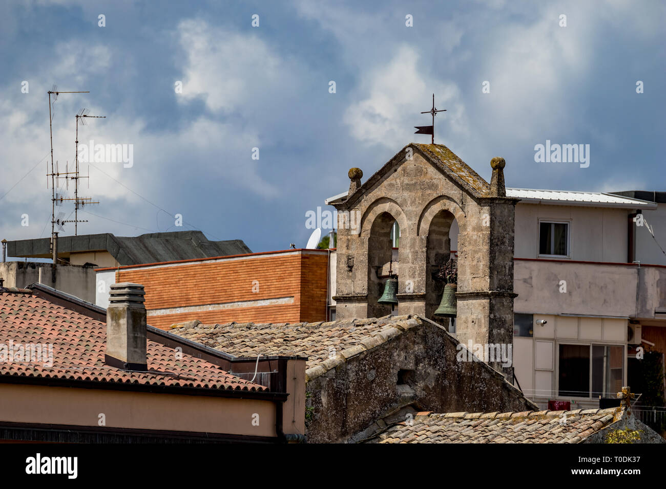 La torre de la iglesia con dos campanas de bronce y el techo, con vista de la calle Cruz, religiosas de la antigua ciudad de Matera, Basilicata, en el sur de Italia, nublado verano cálido Foto de stock