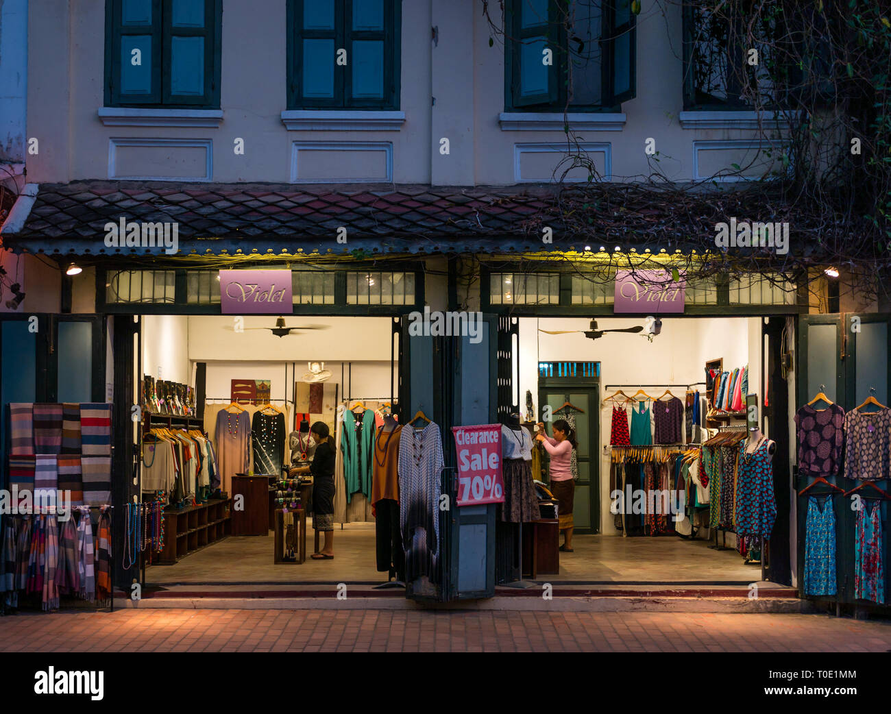 La tienda de ropa para mujer llamada Violet vendiendo vestidos, mantones y joyas abierta por la noche ofreciendo una venta de hasta un 70% de descuento, Luang Prabang, Laos, se Asia Foto de stock