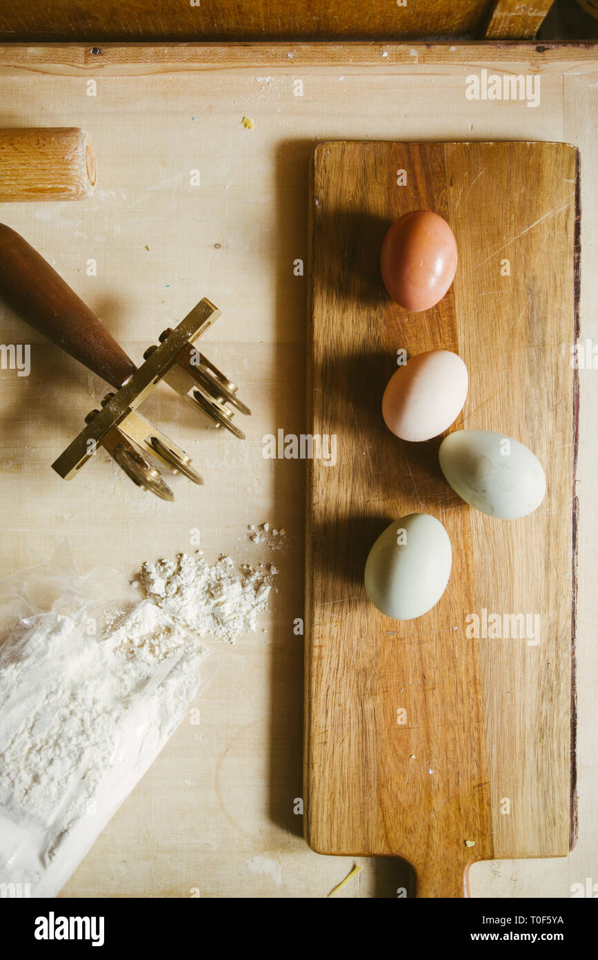 Hacer la pasta en casa, natural de huevo verde oliva, Egger, blanco y marrón, huevo, harina y pasta cutter sobre un fondo de madera Foto de stock