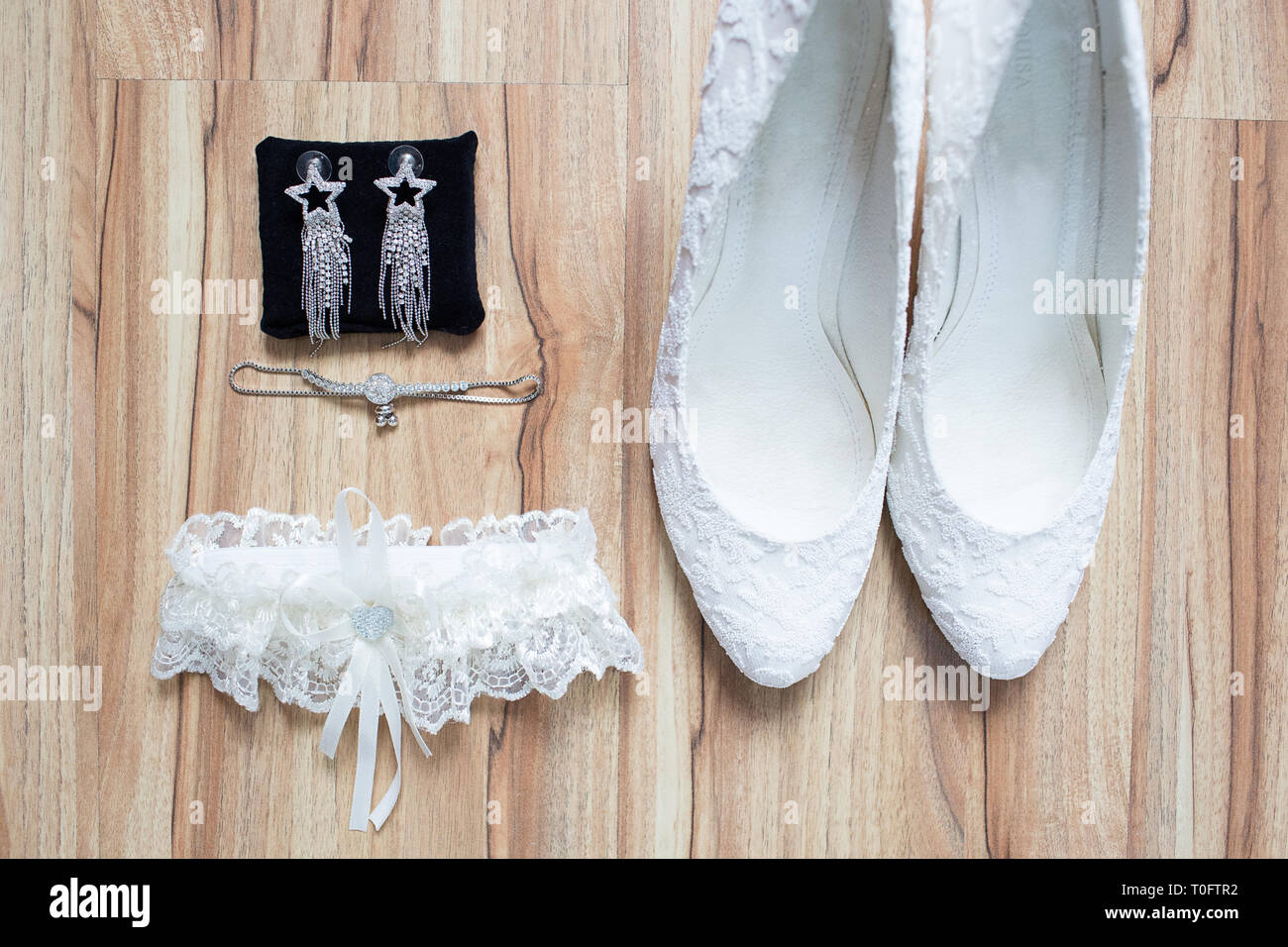 Novia boda accesorio, laicos plana. Zapatos elegantes, aretes, , garter en madera de fondo. Foto de stock