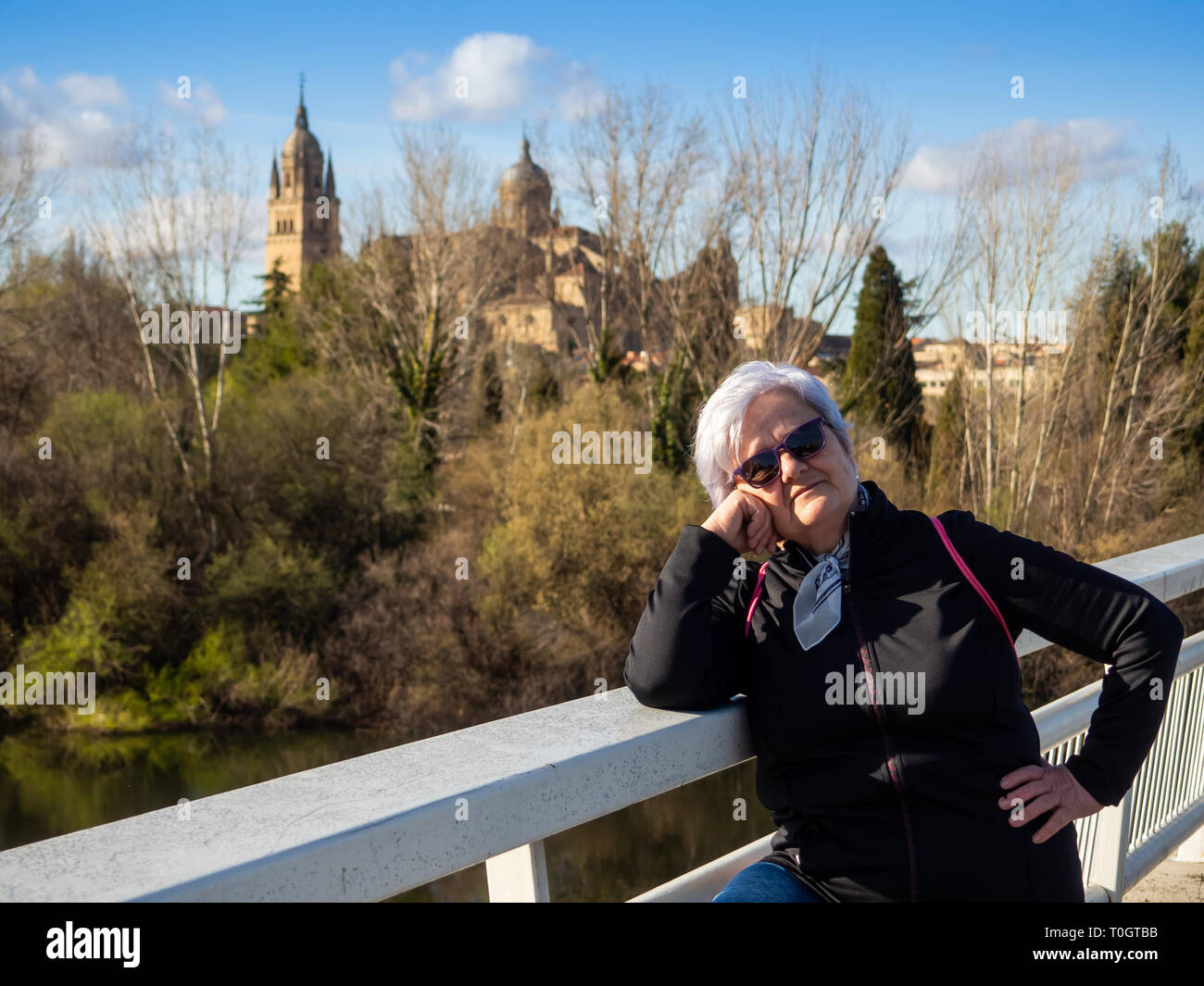 Una mujer mayor con el pelo blanco posando delante de la catedral de Salamanca Foto de stock