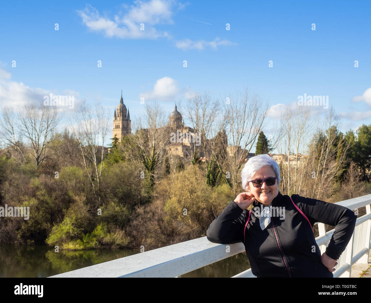 Una mujer mayor con el pelo blanco posando delante de la catedral de Salamanca Foto de stock