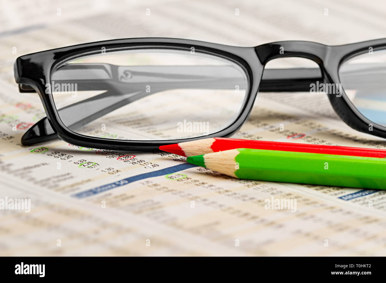 Gafas rojo verde bolígrafo lápiz sobre papel de diario con la tabla de datos de intercambio bursátil finanzas concepto empresarial fondo efectivo Foto de stock
