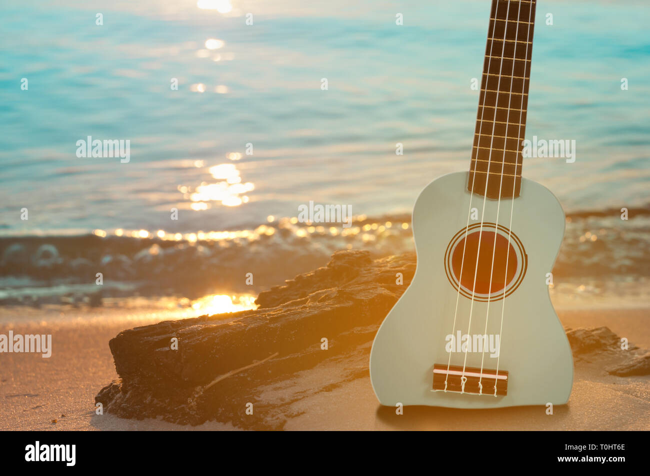 Ukelele guitarra en la playa de arena con aguas claras y cielo azul. Viajes  y el concepto de estilo de vida Fotografía de stock - Alamy