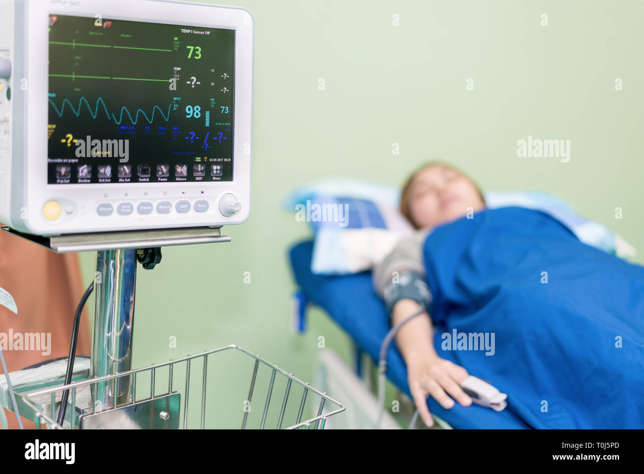 Enfermera asiática tomando la presión arterial de la mujer joven en la sala de urgencias en el hospital. Foto de stock