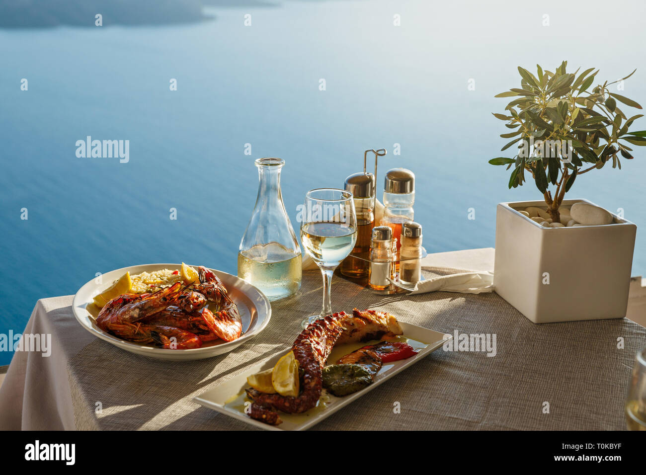 Cena romántica para dos en el sunset.Grecia, Santorini, restaurante en la playa, sobre el volcán. Foto de stock