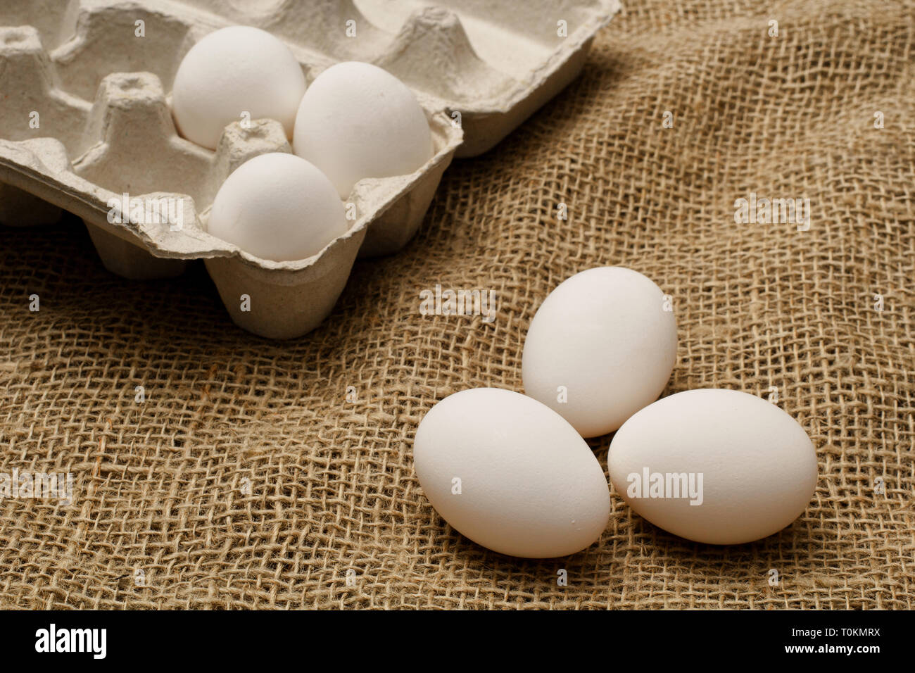 Los huevos y cartón sobre tela de saco de arpillera. Foto de stock