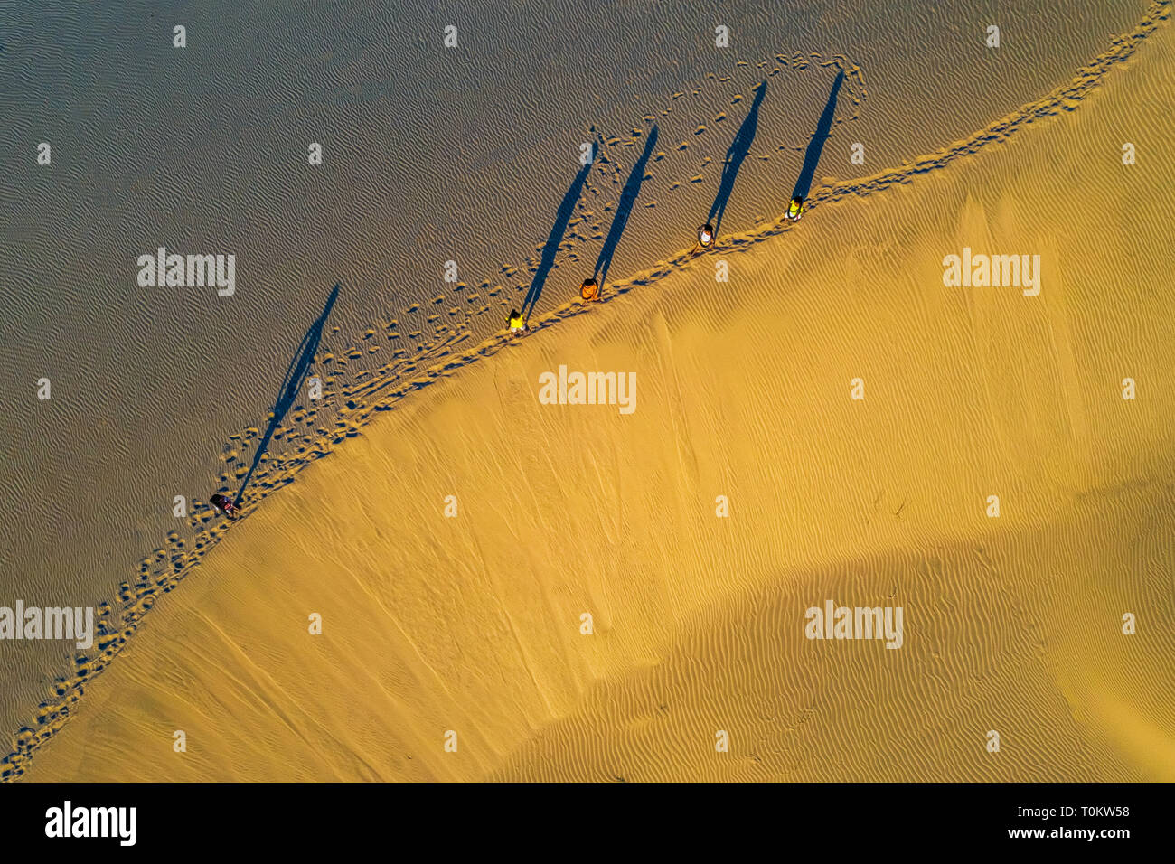 Vista aérea de la mujer que llevaba la cesta al atardecer en Bau Trang duna de arena, como Sun crea gradualmente ajuste hermoso en Mui Ne, Phan Thiet, Vietnam Foto de stock