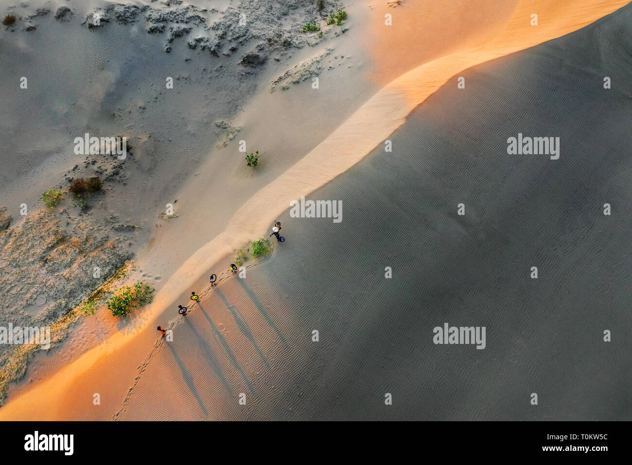 Vista aérea de la mujer que llevaba la cesta al atardecer en Bau Trang duna de arena, como Sun crea gradualmente ajuste hermoso en Mui Ne, Phan Thiet, Vietnam Foto de stock