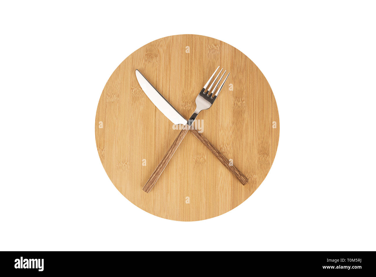 Tenedor y cuchara dispuestas en una placa de madera redondo. Concepto de dieta y ayuno intermitente. Foto de stock