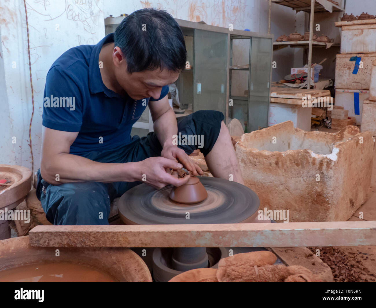 Potter en su taller lanza una olla en el torno de alfarero en Jianshui, prefectura de Honghe, provincia de Yunnan, China. Foto de stock