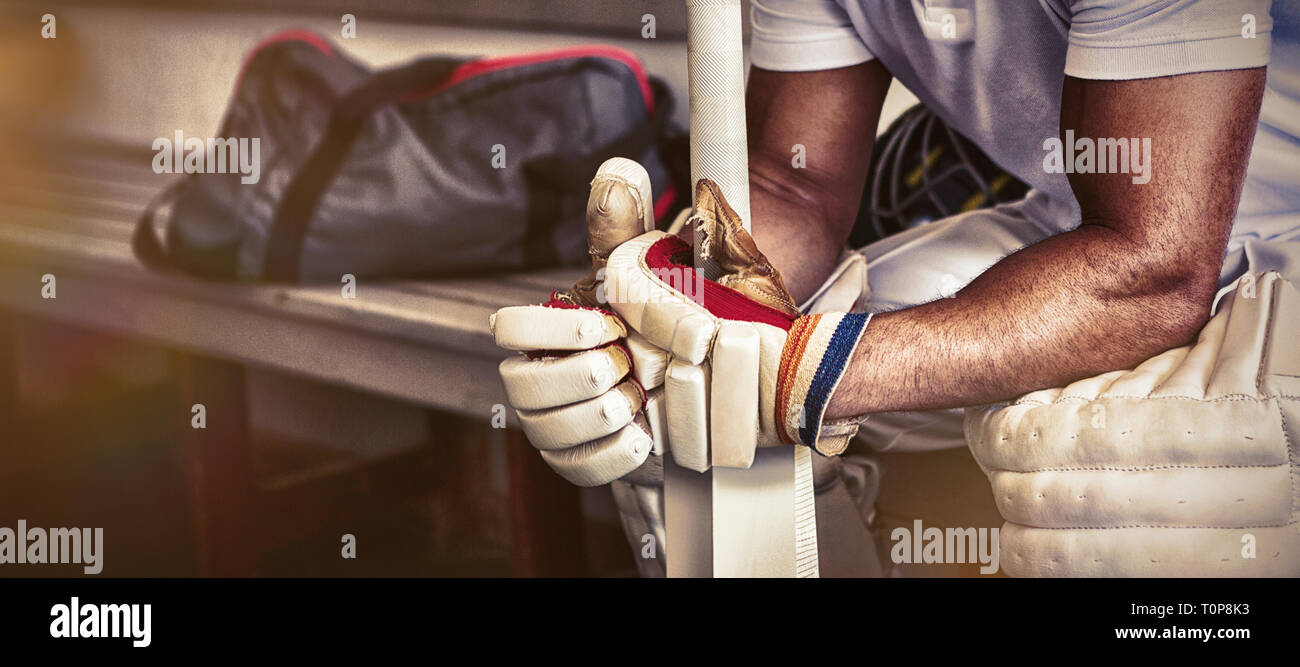 Subrayó cricket jugador sentado en un banco Foto de stock