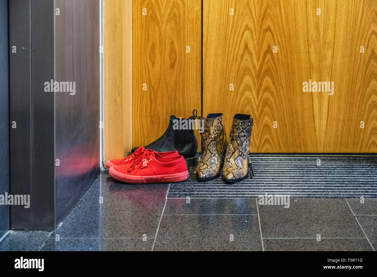 La vida urbana. Considerados los visitantes dejan los zapatos mojados en la  puerta del apartamento. Los formadores de color rojo, negro botas, botines  de piel de serpiente Fotografía de stock - Alamy