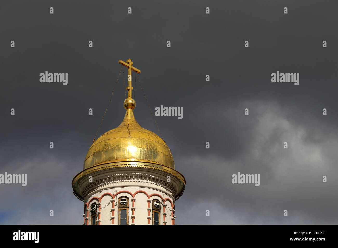 Cúpula dorada del templo cristiano con una cruzada contra la tormenta espectacular cielo con nubes oscuras. Iglesia Ortodoxa, Fondo para la tarjeta religiosa Foto de stock