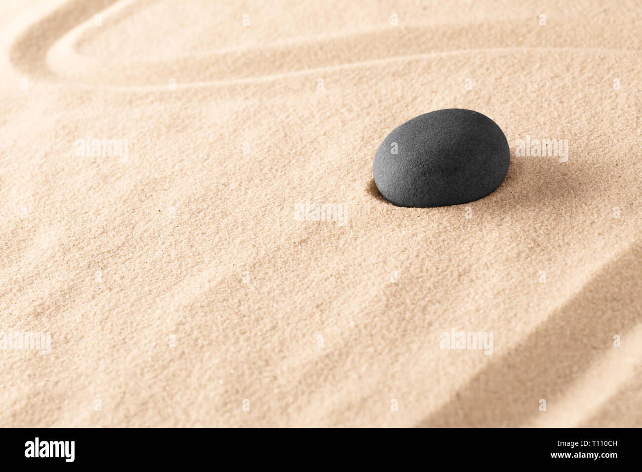 Basalto negro meditación Zen Stone en un jardín de arena japonés. El minimalismo para centrar la concentración en la curación espiritual. Una terapia alternativa en el balneario wel Foto de stock