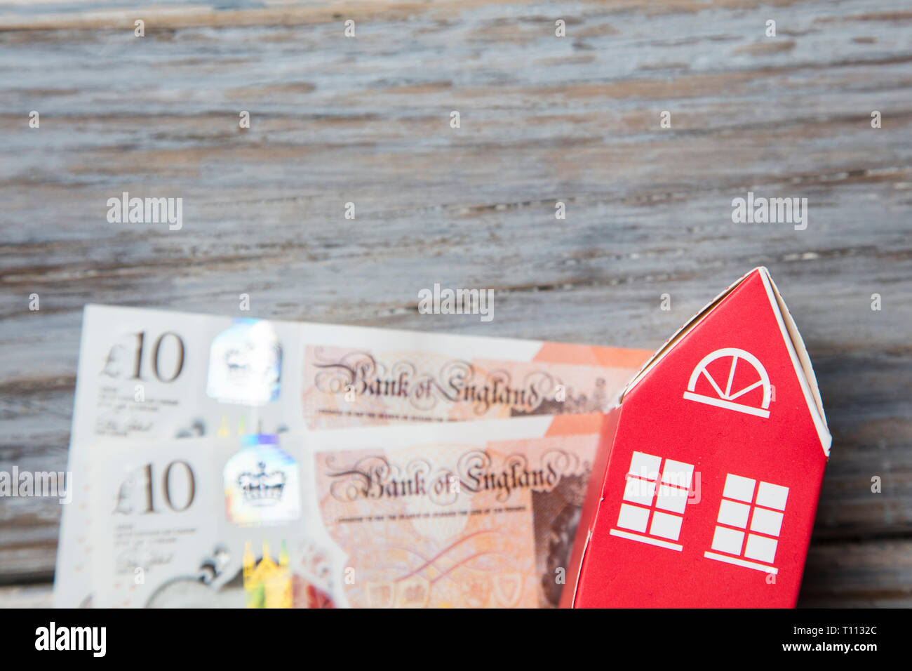 El costo de las viviendas. Casa de juguetes de papel con notas de moneda británica Foto de stock