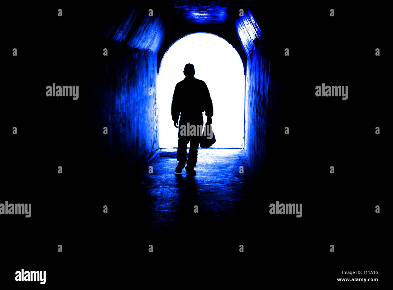 Persona caminando a través de un túnel hacia la luz al final. El cumplimiento de meta o salir de la oscuridad. Foto de stock