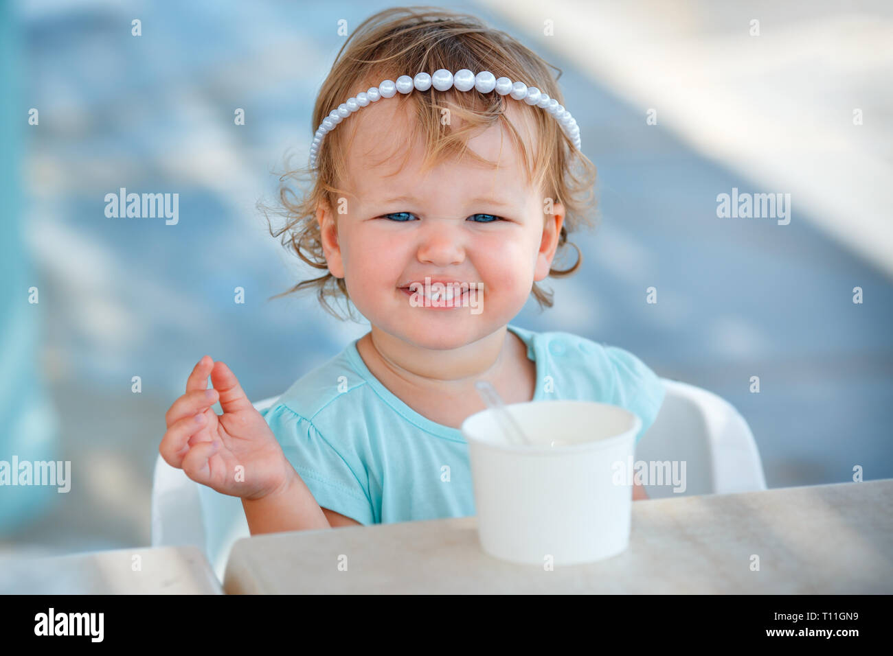 Adorable niña comer helado en la cafetería al aire libre en el hermoso día de verano Foto de stock