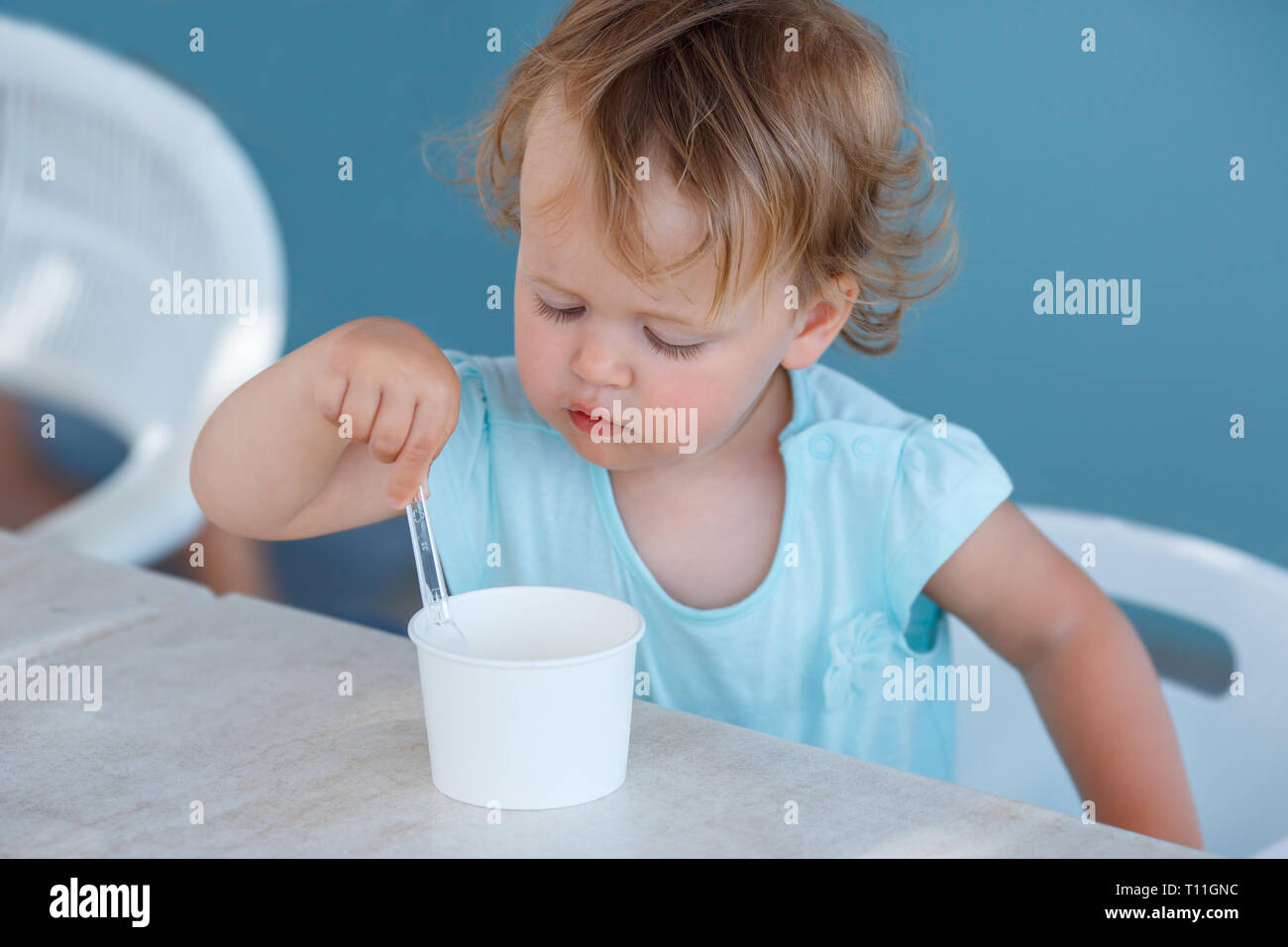 Adorable niña comer helado en la cafetería al aire libre en el hermoso día de verano Foto de stock