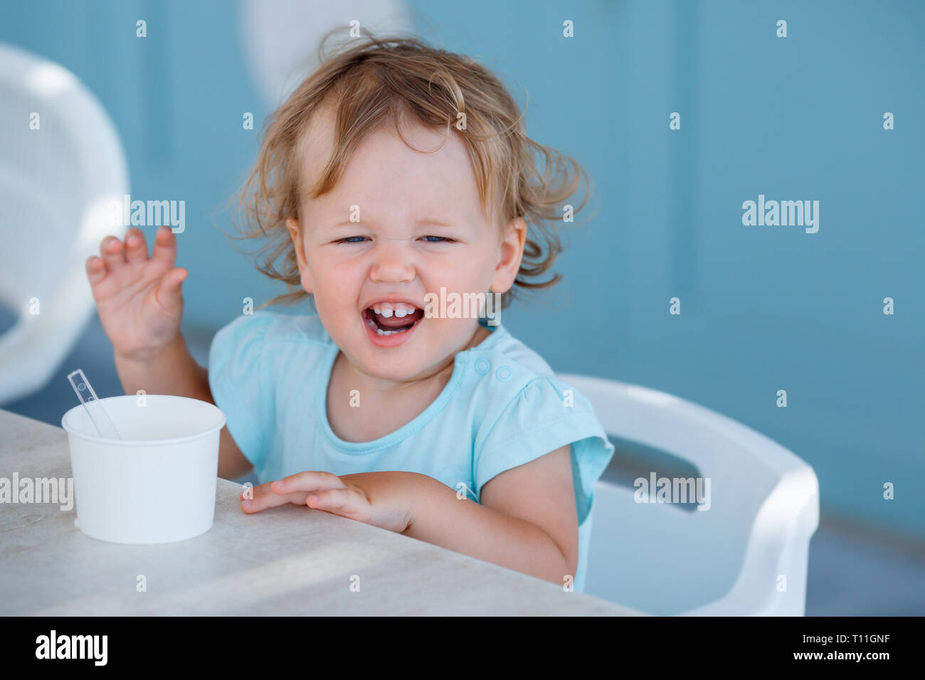 Adorable niña comer helado en la cafetería al aire libre en el hermoso día de verano Foto de stock