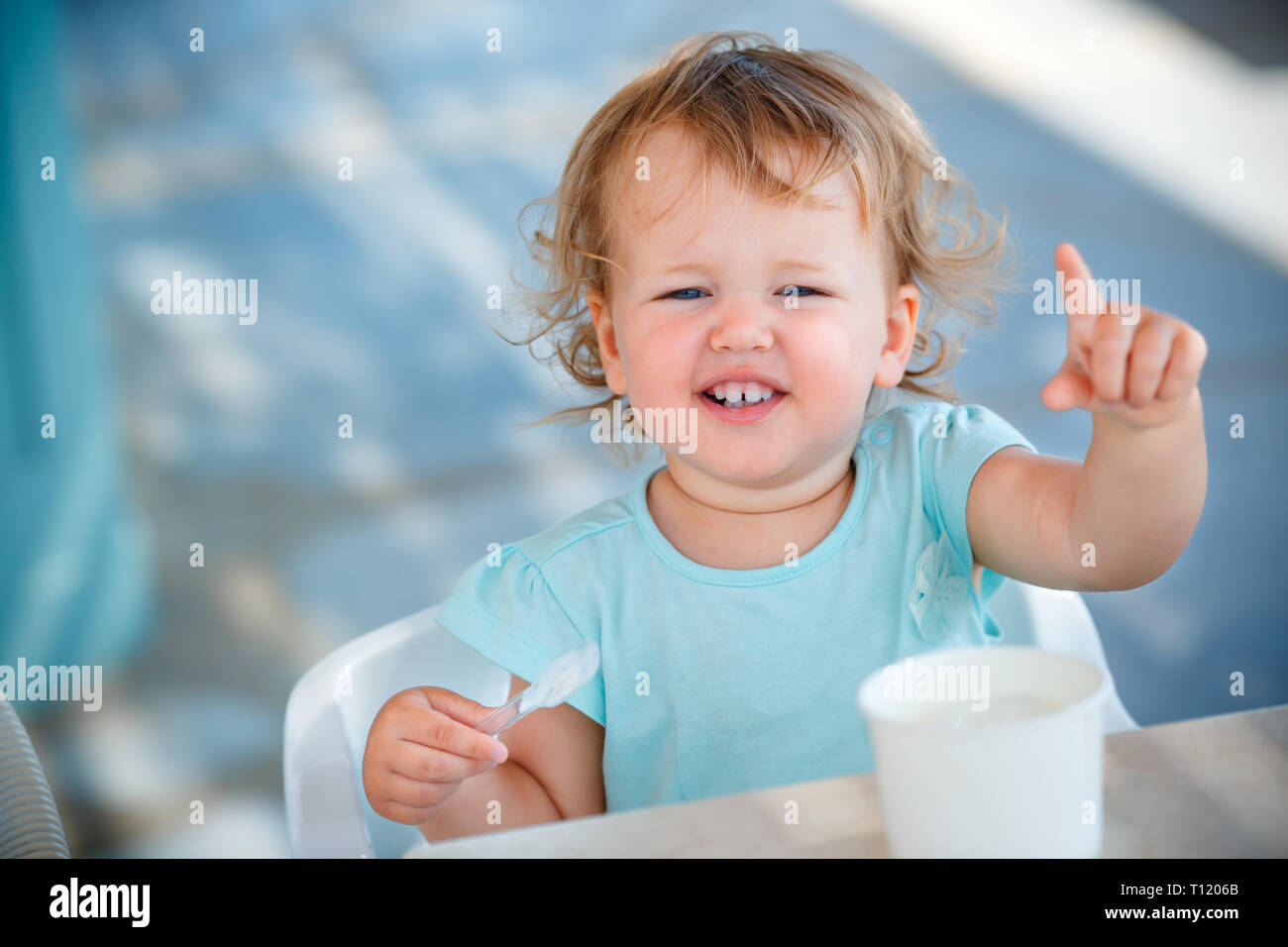 Adorable niña feliz comer helado en la cafetería al aire libre en el hermoso día de verano Foto de stock