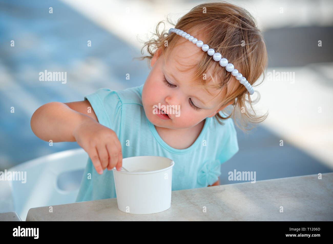 Adorable niña comer helado en la cafetería al aire libre en el hermoso día de verano Foto de stock