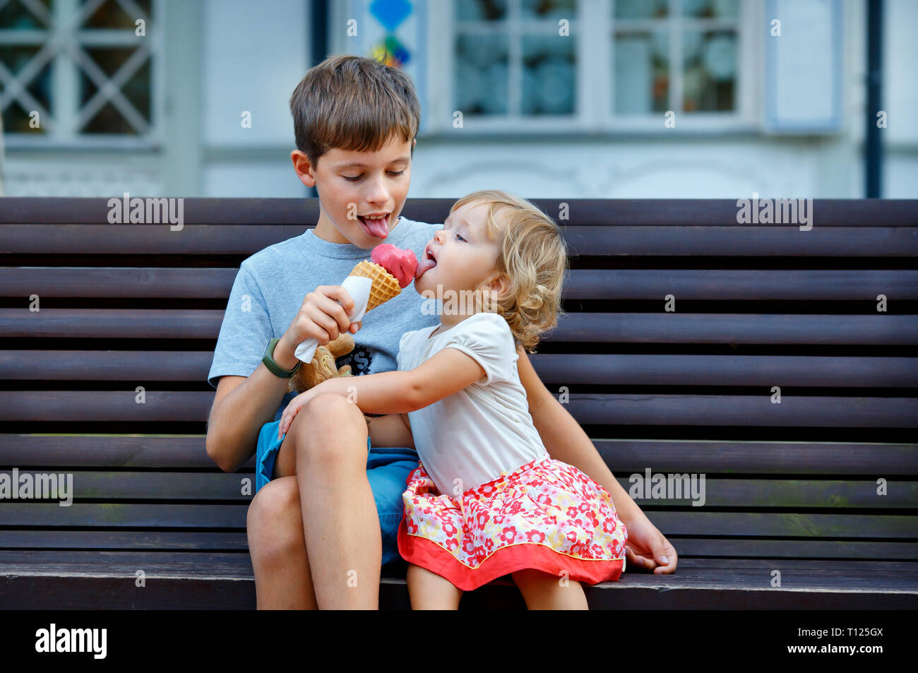 Gran hermano dando su helado a hermana pequeña piscina Foto de stock