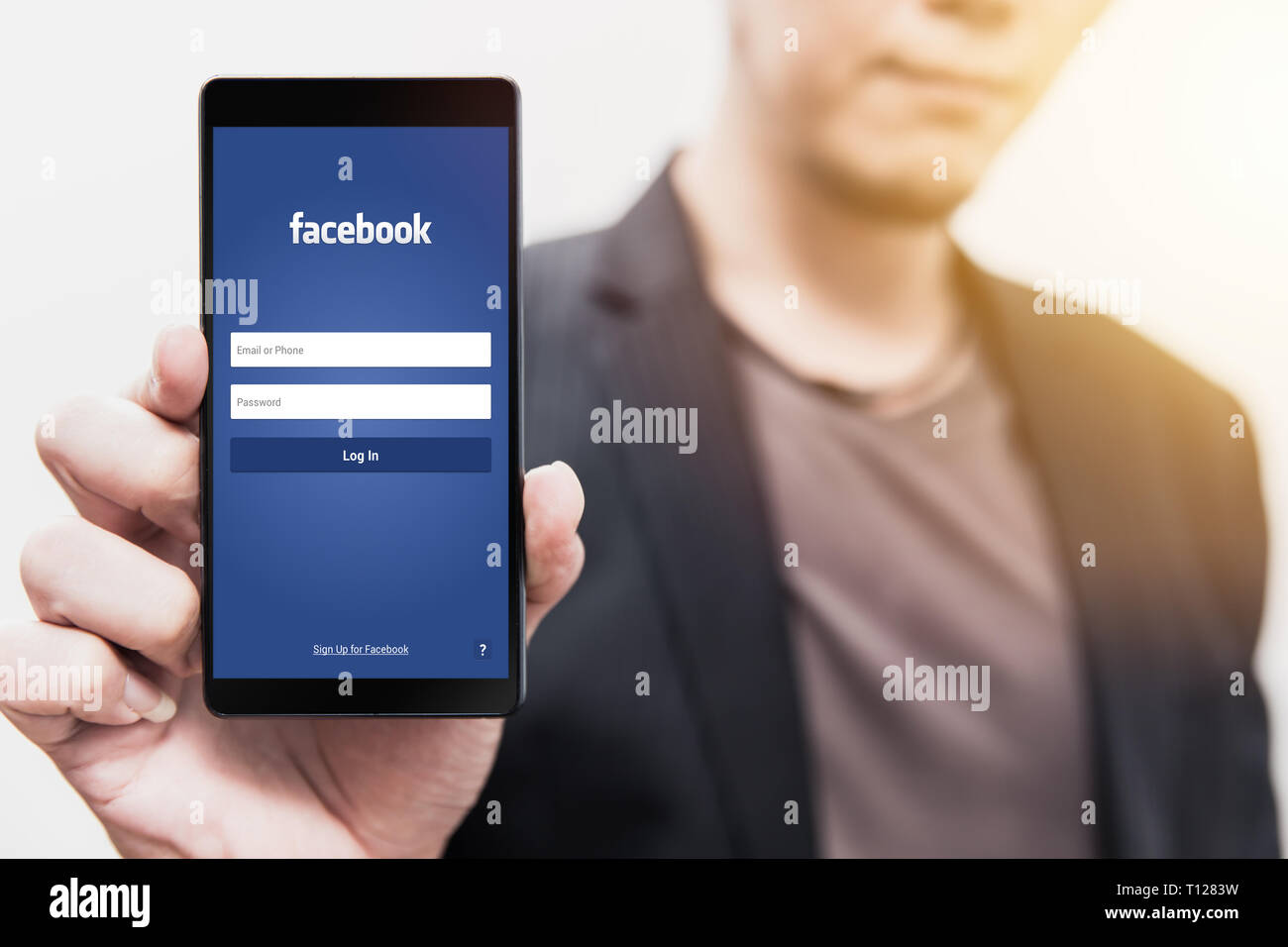 Empresario Mostrar página de inicio de Facebook en su smartphone para utilizar phone app social para los negocios. El 3 de agosto de 2018, Bangkok, Tailandia. Foto de stock