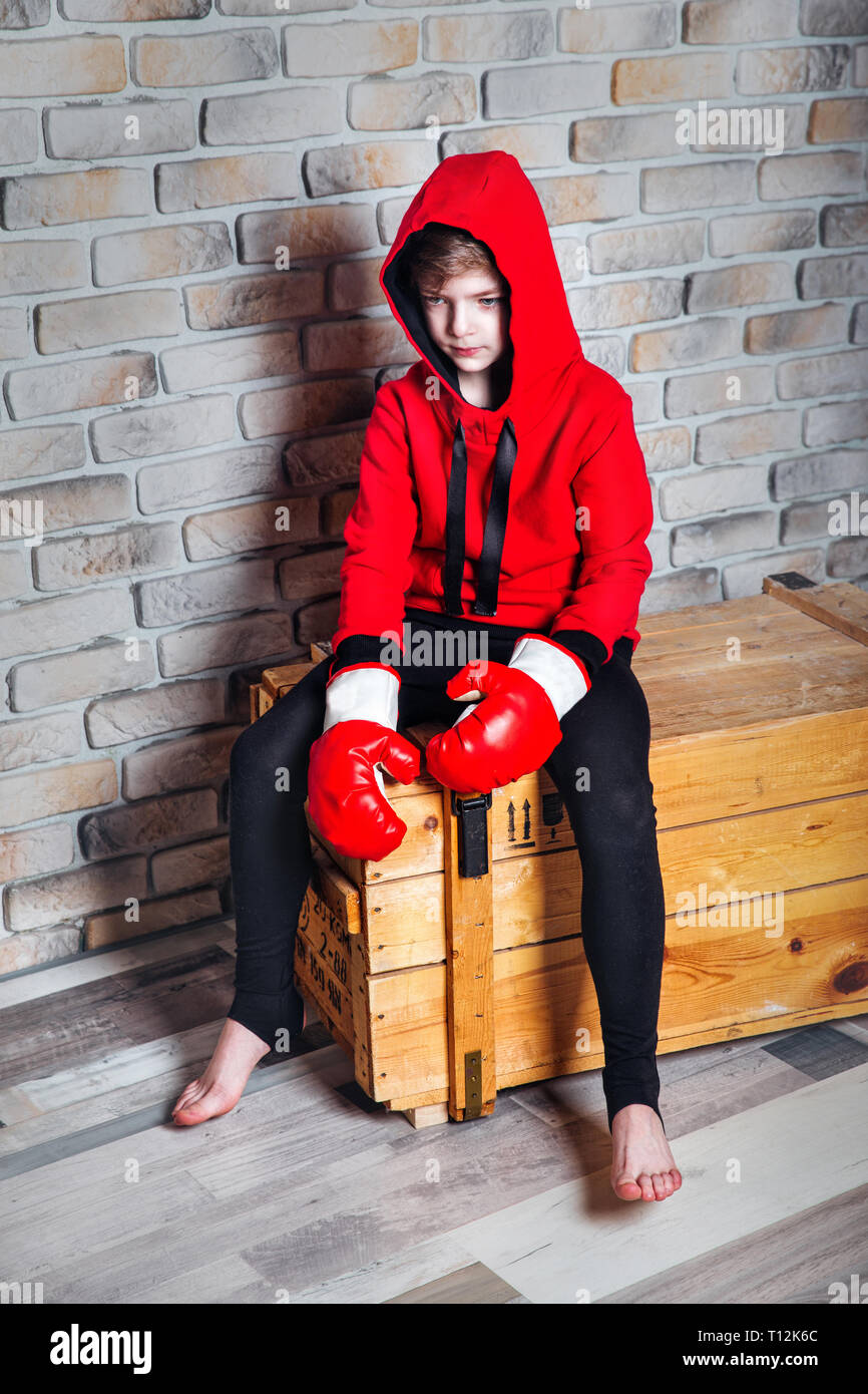Joven boxeador . Chico boxer con cabello rubio vestirse en rojo sudadera  llevando guantes boxeo posando en un estudio Fotografía de stock - Alamy