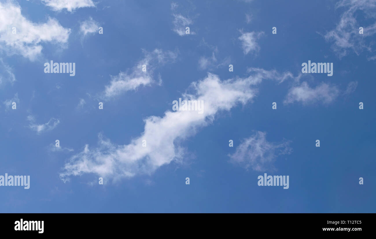 Feathery retroiluminado hinchadas nubes flotando en un cielo azul puro Foto de stock