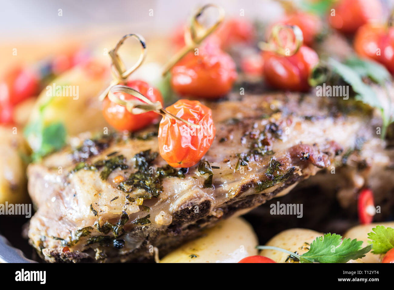 Pierna de cordero asado en el horno con tomates, patatas verdes y Romero  Fotografía de stock - Alamy