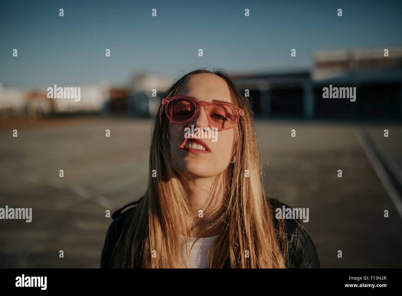 Retrato de mujer joven con actitud desafiante con gafas de sol al aire libre Foto de stock