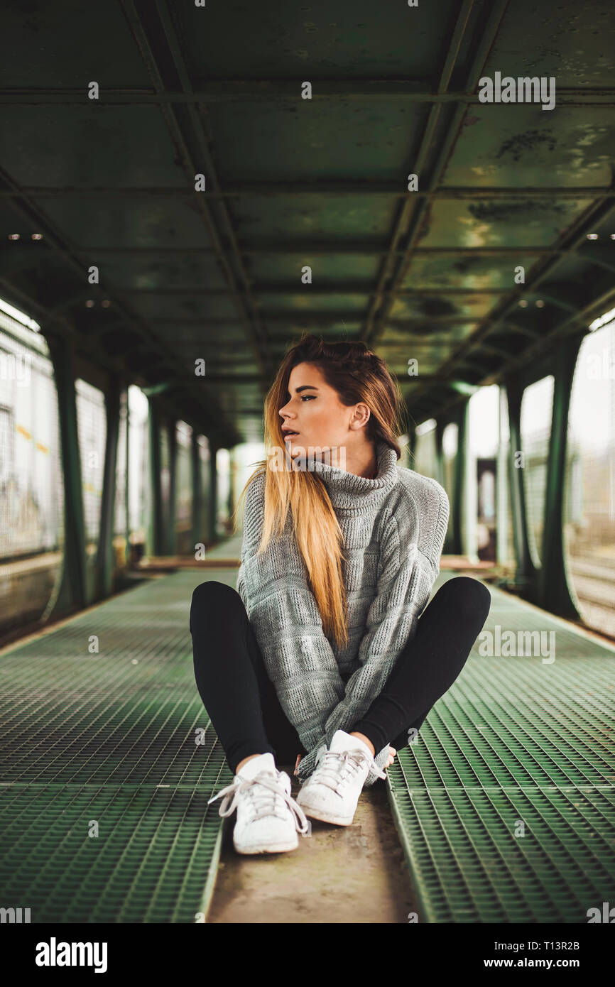 Joven Mujer sentada en un vagón de tren abandonada Foto de stock