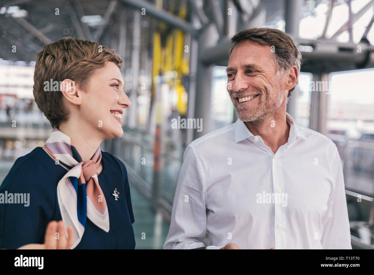 Feliz empleado de aerolínea hablando a los pasajeros en el aeropuerto. Foto de stock