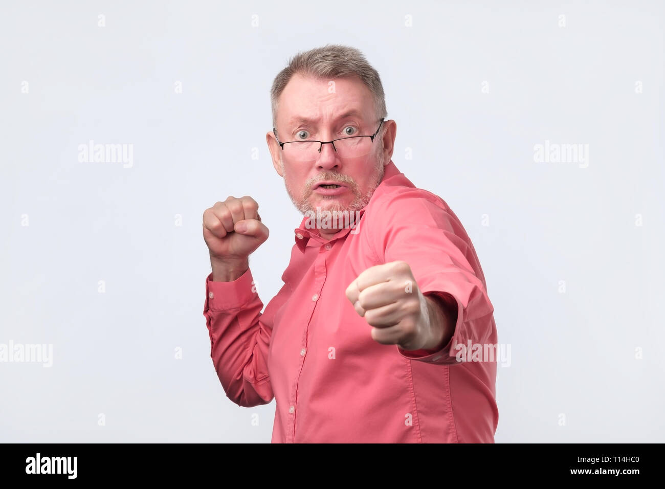 Hombre en camisa roja de pie en pose de boxeador, planteadas con los puños como si defender Foto de stock