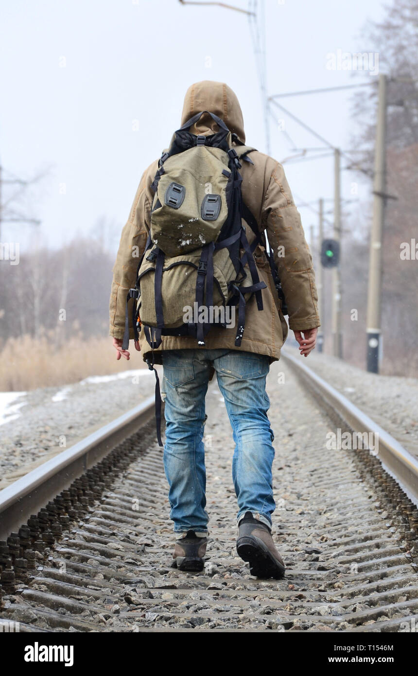 Un hombre con una mochila grande va por delante en la vía férrea durante la  temporada de invierno Fotografía de stock - Alamy