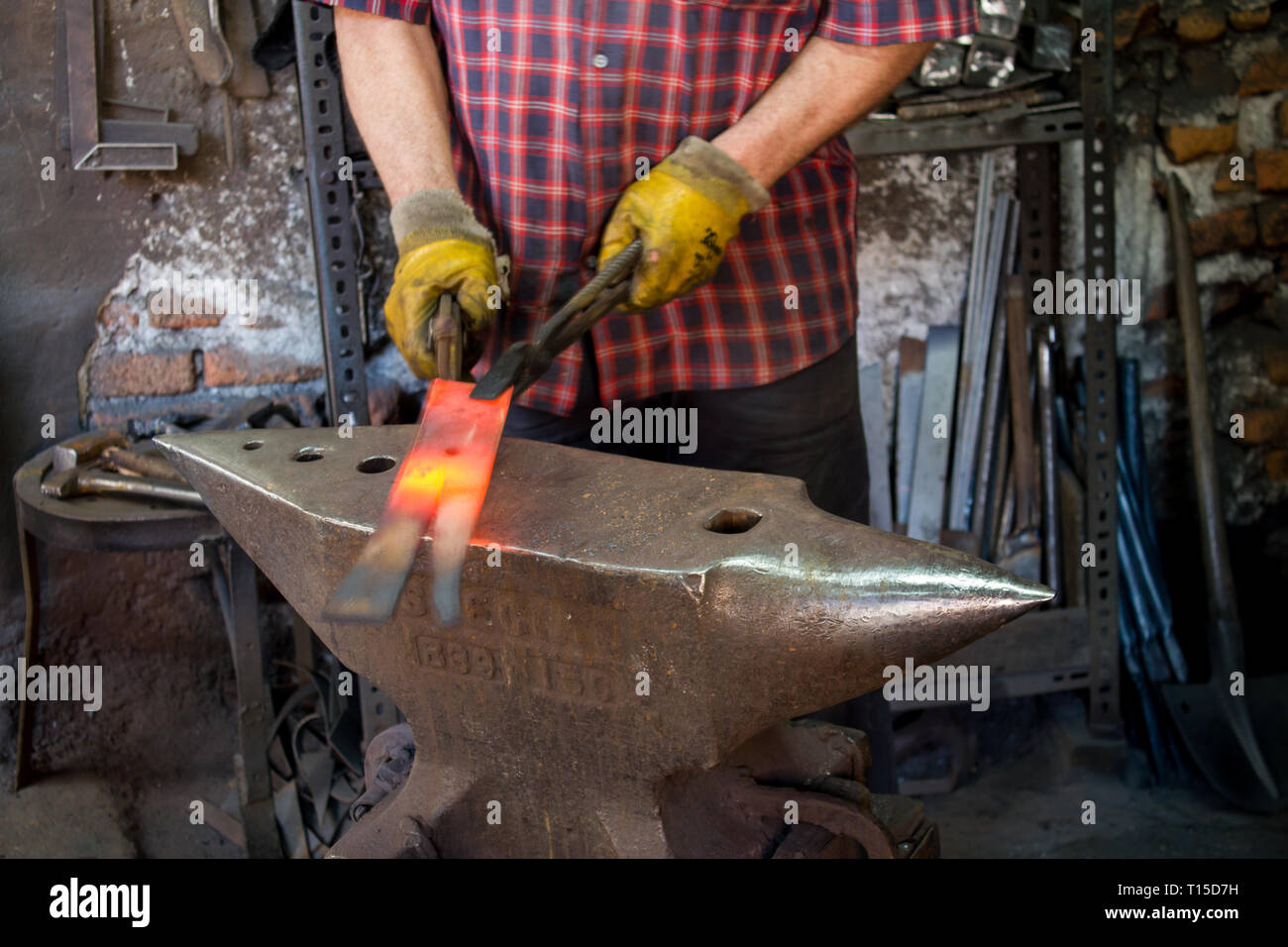 Herrero trabaja en un yunque. producto de forja maestra. herramientas y  yunque de herrero. herrero trabajando al aire libre.