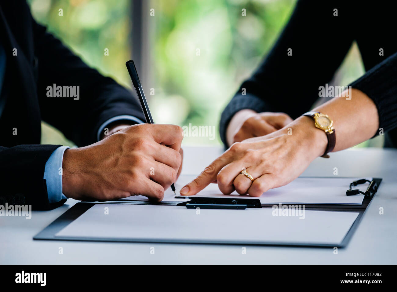 Vista lateral de la empresaria de cultivo apuntando a contrato al empresario con el lápiz en la mesa en la oficina Foto de stock