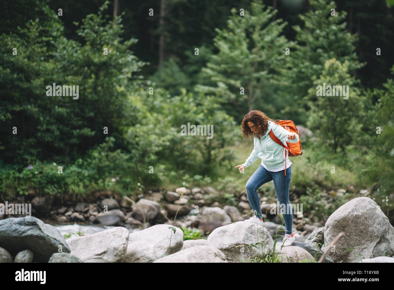 Bella mujer caminante con mochila cerca de río de montaña salvaje. Foto de stock
