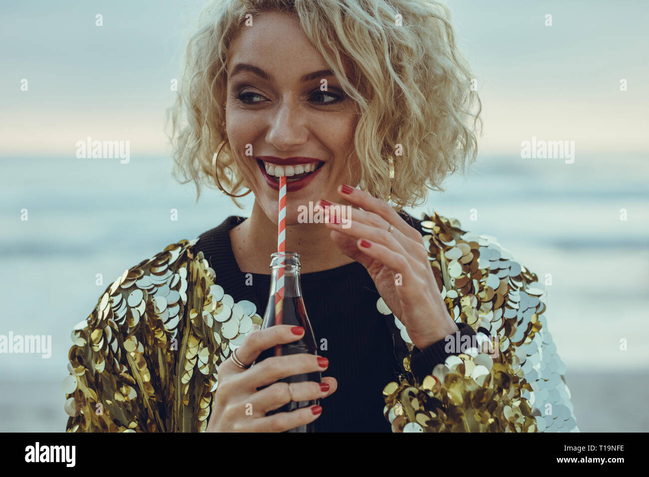 Feliz joven beber un refresco al aire libre. Mujeres beber bebida fría